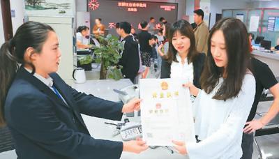 河北省承德市網(wǎng)絡(luò)代購經(jīng)營者陳晨(右)從工作人員手中接過帶有統(tǒng)一社會信用代碼的營業(yè)執(zhí)照。 劉環(huán)宇攝(人民圖片)