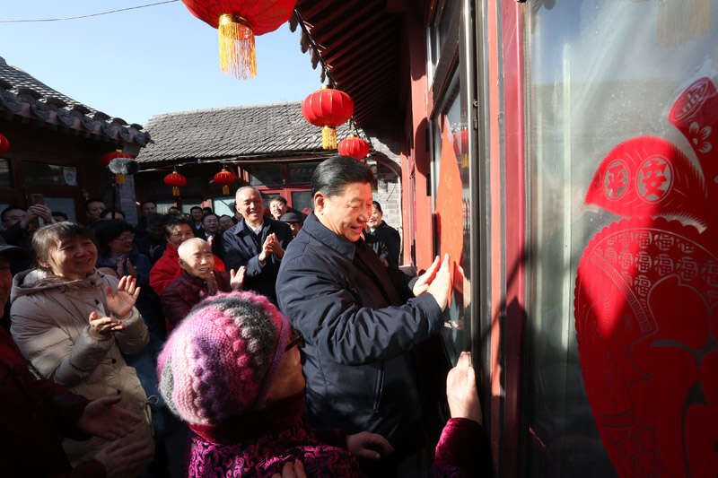 2019年2月1日上午，習近平在北京前門東區(qū)草廠四條胡同32號院，高興地拿起一幅“?！弊?，親自貼到門上，給這里的老街坊們拜年。新華社記者 鞠鵬 攝